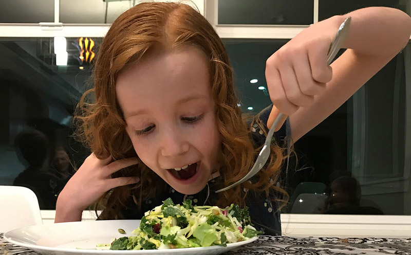 girl eating salad happily who isn't picky about vegetables