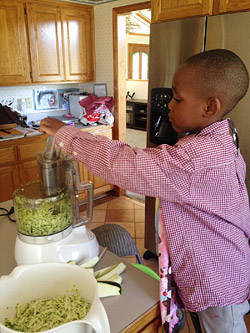 boy shredding zucchini for dinner